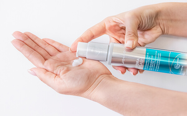 HydraSplash-styler-in-hand Hair styling product being squuezed out of bottle
